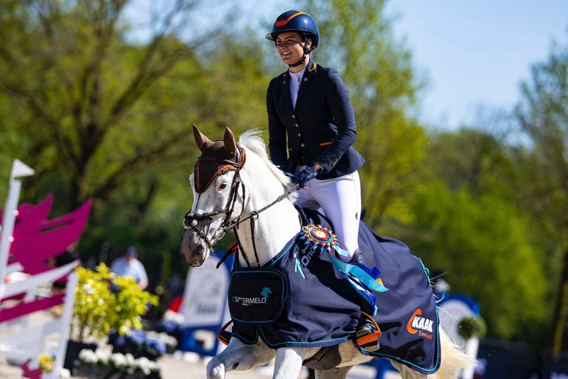 Kristy Snepvangers riding her grey horse during price giving in a JuulC show jacket