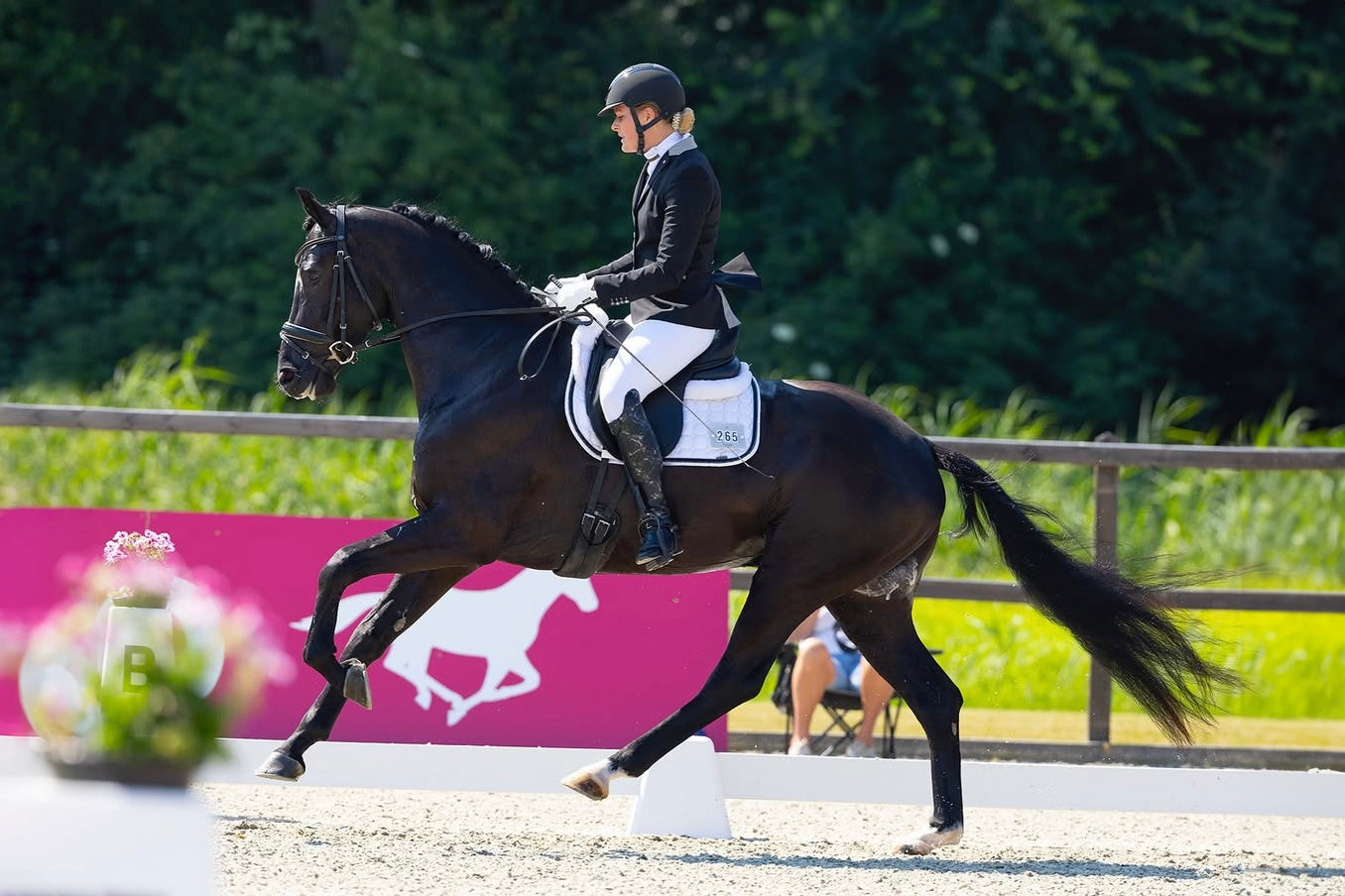 Lisa Veldhuisen riding an extended trot in a young horse competition, wearing a JuulC show coat