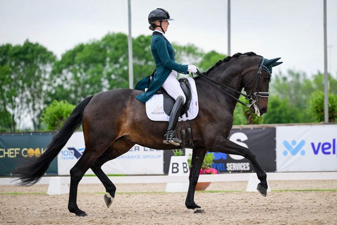 Romy Veldmeijer riding an extended trot at an outdoor show while wearing her JuulC dressage tailcoat