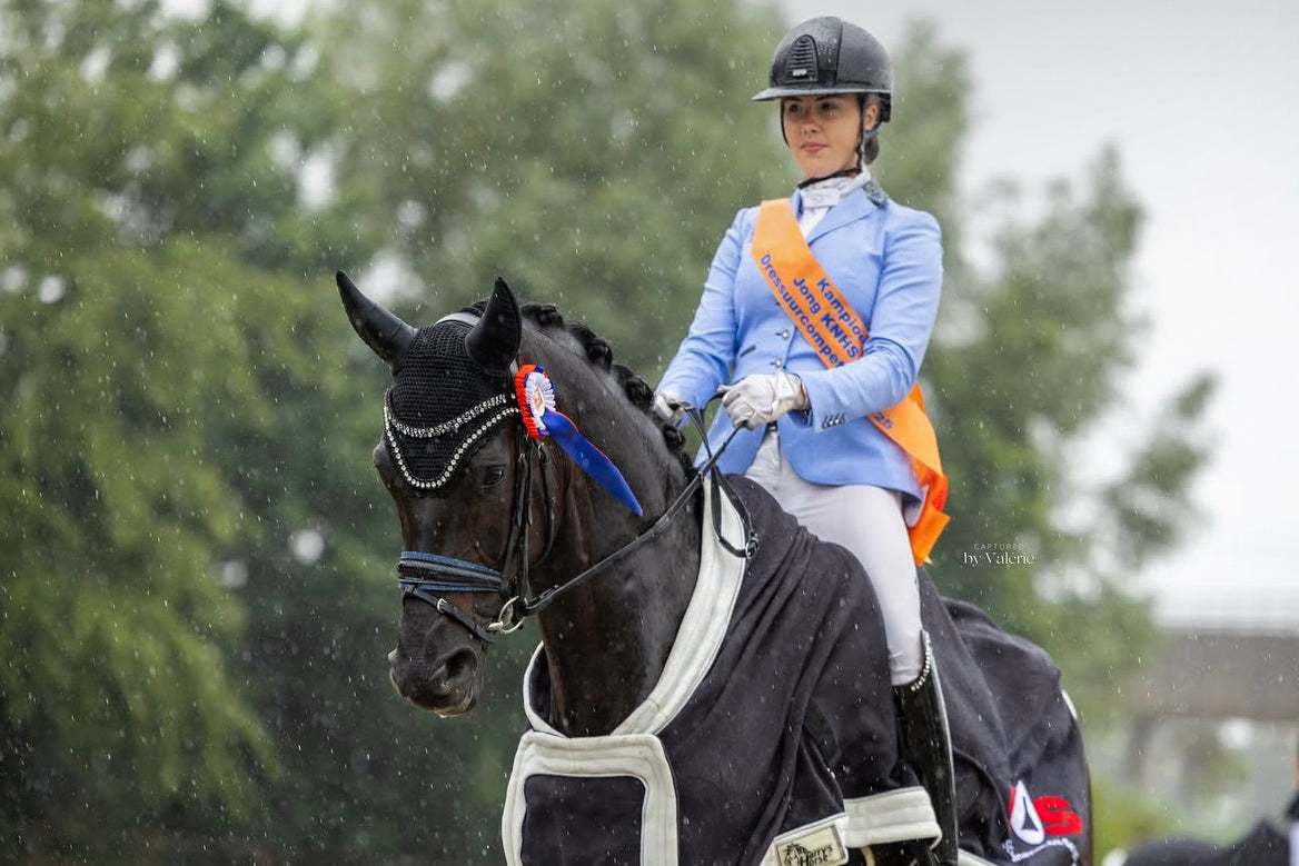 Romy Veldmeijer showing her black mare in a prize giving, wearing her JuulC competition jacket