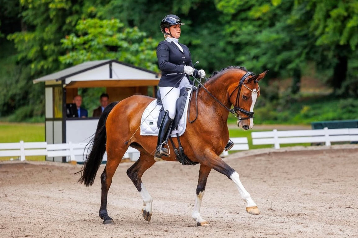 Ramona Edler riding an extended trot with her horse in their dressage test, wearing a JuulC show jacket