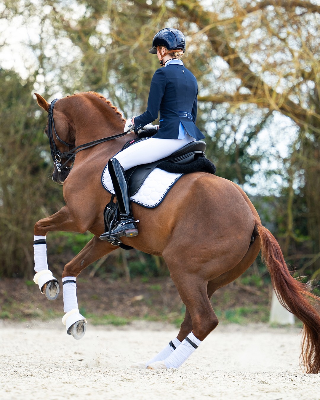 Model riding a canter pirouette with her horse wearing JuulC' Navy Light Blue Women's Show Jacket 